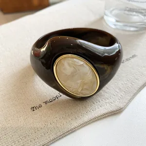 Close-up of marbled acrylic bangle with gold-trimmed cream oval inlay detail