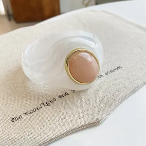 Close-up of marbled white acrylic bangle featuring a peach-colored round cabochon