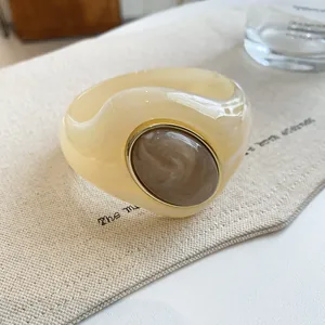 Close-up detail of a marbled acrylic bangle featuring irregular shape and gold frame
