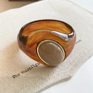 Close-up of an amber marbled acrylic bangle with a grey stone inlay in a gold frame