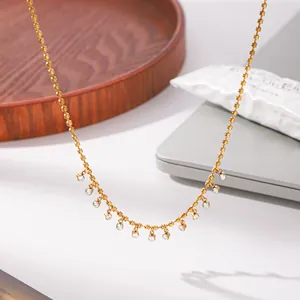 Detail view of a 18K gold plated titanium steel necklace with dangling CZ stones.