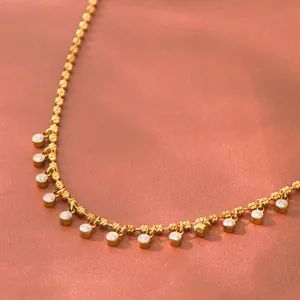 Macro detail of luxury 18K gold plated titanium steel necklace with round zircon charms.