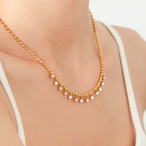 Detailed close-up of gold titanium steel necklace with dangling zircon stones on skin.