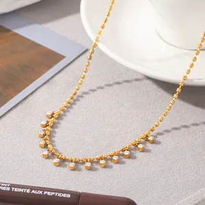 Close-up of gold beaded necklace featuring zircon circular dangles on a grey surface