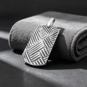 Macro detail of men's titanium steel dog tag pendant with textured diagonal pattern