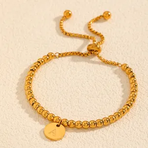 Gros plan de qualité d'un bracelet en perles d'acier plaqué or avec pendentif initiale A
