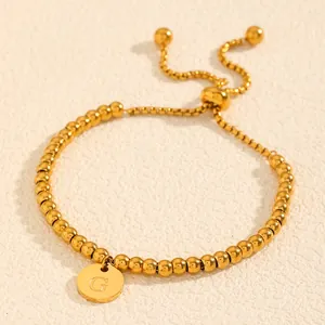 Vue détaillée d'un élégant bracelet en perles d'acier doré avec pendentif lettre G gravée
