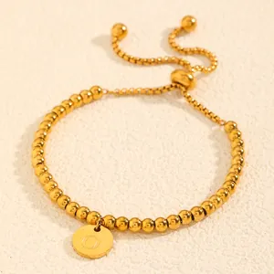 Vue détaillée d'un bracelet en perles d'acier doré avec médaille gravée réglable