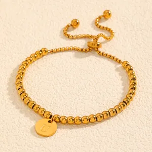 Détail d'un bracelet à perles plaqué or avec un pendentif gravé de la lettre U