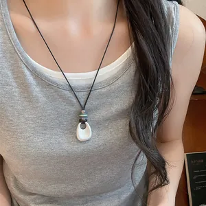 Minimalist silver matte teardrop pendant necklace with decorative beads worn by a woman