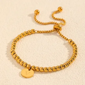 Détail d'un élégant bracelet en perles d'acier titane doré avec pendentif lettre V