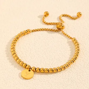 Gros plan d'un bracelet en perles d'acier titane doré avec breloque initiale 'Y' gravée