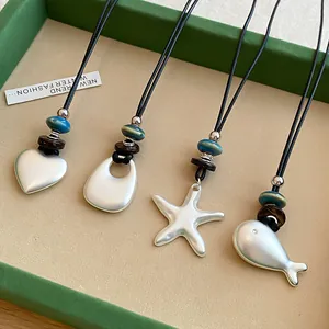 Detailed macro view of silver star and fish pendants on minimalist black cord necklaces