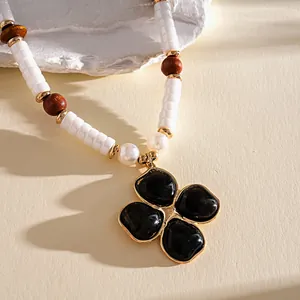 Primo piano di una collana vintage con ciondolo a fiore in resina nera e perle.