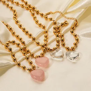 Gros plan de chaînes à billes en acier doré avec pendentifs cœurs roses et clairs