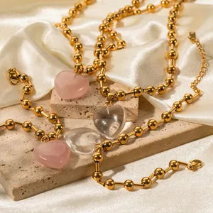 Gros plan détaillé de colliers à billes dorées avec pendentifs en forme de cœur rose