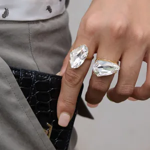 Gros plan de bagues en cristal de verre irrégulières surdimensionnées sur une main dorée