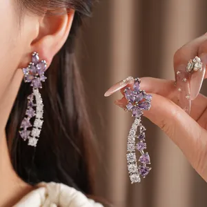 Nahaufnahme von eleganten lila Blumen-Ohrhängern mit funkelnden Edelsteinen für einen Luxus-Look