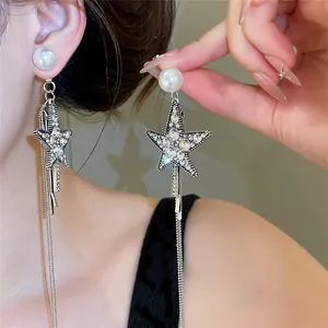 Nahaufnahme von eleganten Stern-Ohrringen und Haarspangen mit weißen Perlen und Quasten