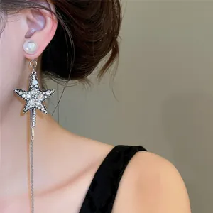 Detaillierte Nahaufnahme eines sternförmigen Strass-Ohrrings mit Perle und langer Quaste