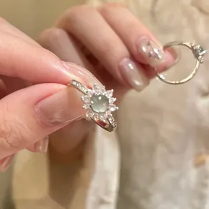 Close-up of a vintage palace style zircon ring with a green gem held by hand