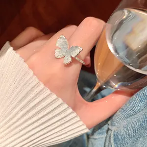 Detailed close-up of a vintage butterfly ring with sparkling zircons on finger.