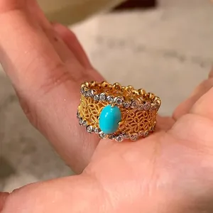 Close-up of a vintage court-style ring with turquoise stone and sparkling zircons