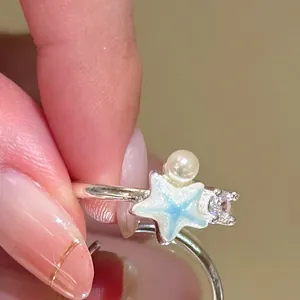 Macro view of a silver ring featuring a blue starfish, pearl, and sparkling zircon
