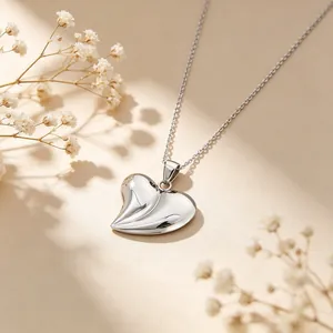 Gros plan d'un collier avec pendentif en forme de cœur 3D argenté sur fond floral.