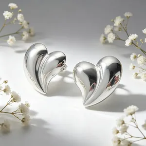Gros plan de boucles d'oreilles cœur 3D argentées avec décor de fleurs blanches délicates