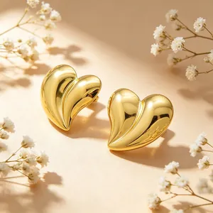 Gros plan de boucles d'oreilles cœur 3D en acier inoxydable plaqué or 18 carats, fini poli.