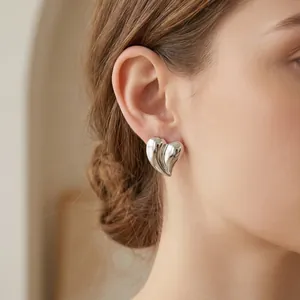 Gros plan d'une boucle d'oreille cœur 3D argentée avec texture nervurée.