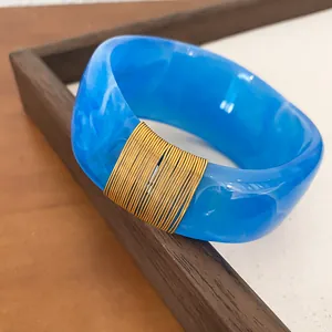 Detailed view of a blue marbled resin bangle featuring elegant gold wire wrap design