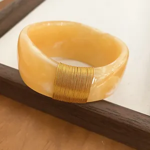 Detailed close-up view of a marbled resin bangle featuring elegant gold wire wrapping detail