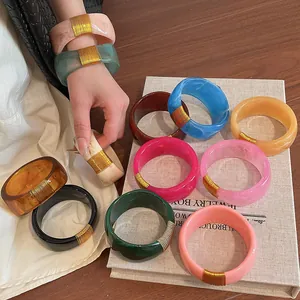 Detailed view of colorful wide resin bangles with decorative gold wire wrapping