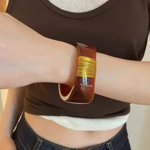 Close-up detail of a wide amber resin bangle featuring elegant gold wire wrapping design