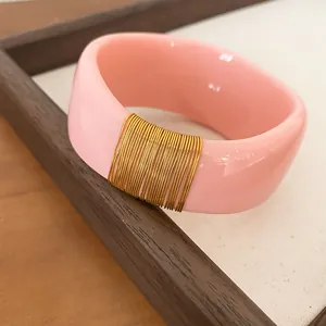 Detailed macro view of wide pink resin bangle with decorative gold wire wrapping