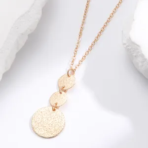 Detailed view of tiered gold metal disc necklace with unique textured dot pattern.