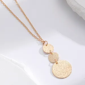 Close-up detail of gold textured triple disc necklace with geometric metal pendants