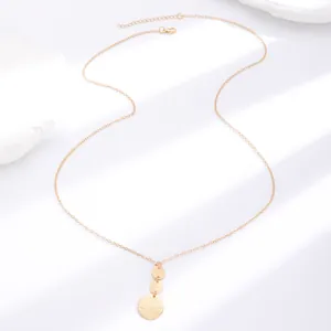 Close-up of golden necklace with triple textured disc pendants on white stone background