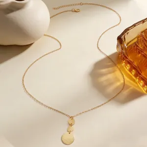 Detailed macro shot of a geometric gold disc necklace featuring unique hammered texture