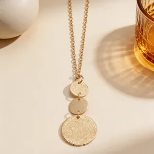 Close-up detail of three tiered gold circular pendants featuring a textured stippled finish.