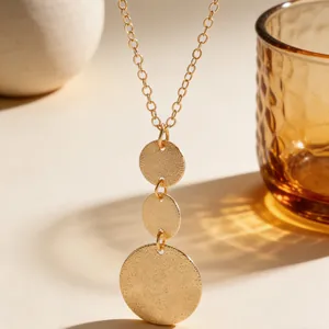 Detailed view of gold tiered geometric round textured pendants on a link chain.