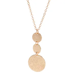 Close-up detail of a gold geometric necklace featuring three textured circular pendants