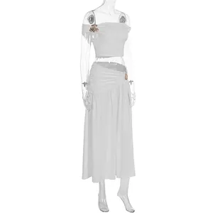 Elegant white two-piece set featuring off-shoulder top and ruched maxi skirt with metal flower