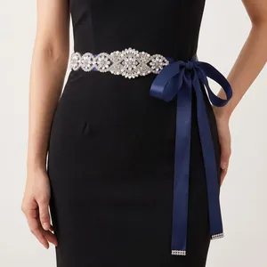 Detailed view of an intricate rhinestone and pearl bridal sash on a black evening dress