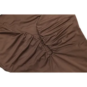 Gros plan sur la texture froncée et le détail ajouré élégant de cette mini-robe marron