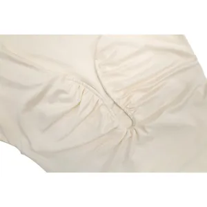 Détail du design ajouré froncé sur une robe courte beige sans manches et moulante