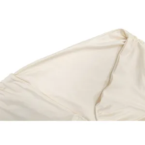 Gros plan sur le tissu en satin beige lisse et le détail du décolleté d'une robe sans manches