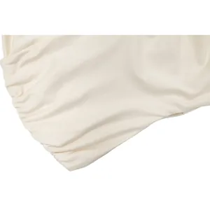 Gros plan sur la texture du tissu froncé de cette mini-robe ajustée de couleur crème